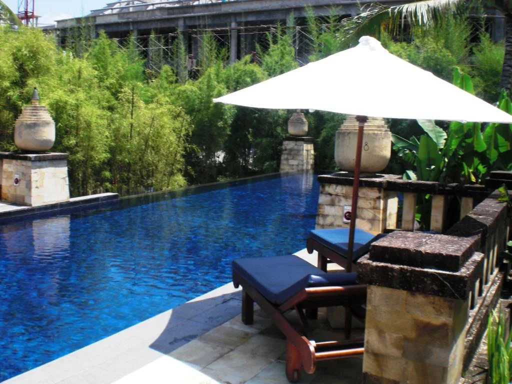 Blue-tiled pool and shaded loungers at Conrad Bali.