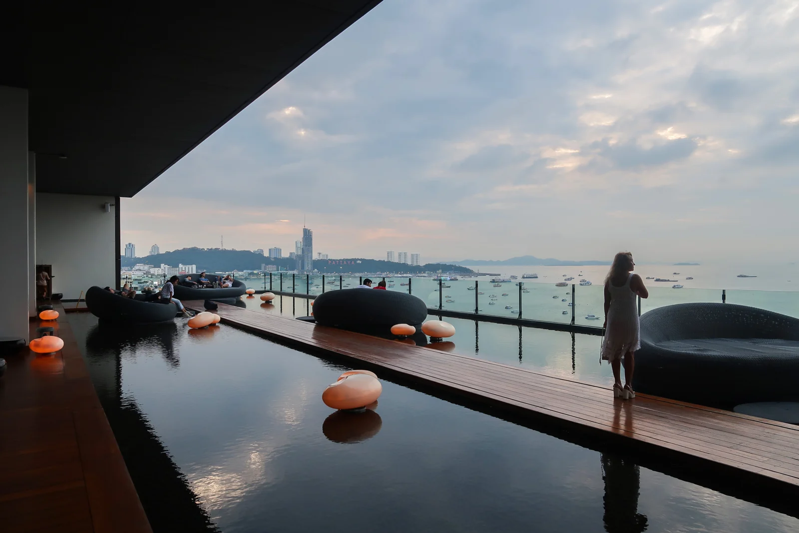 Terrace seating and reflecting pool at Hilton Pattaya overlooking Pattaya Bay at dusk.